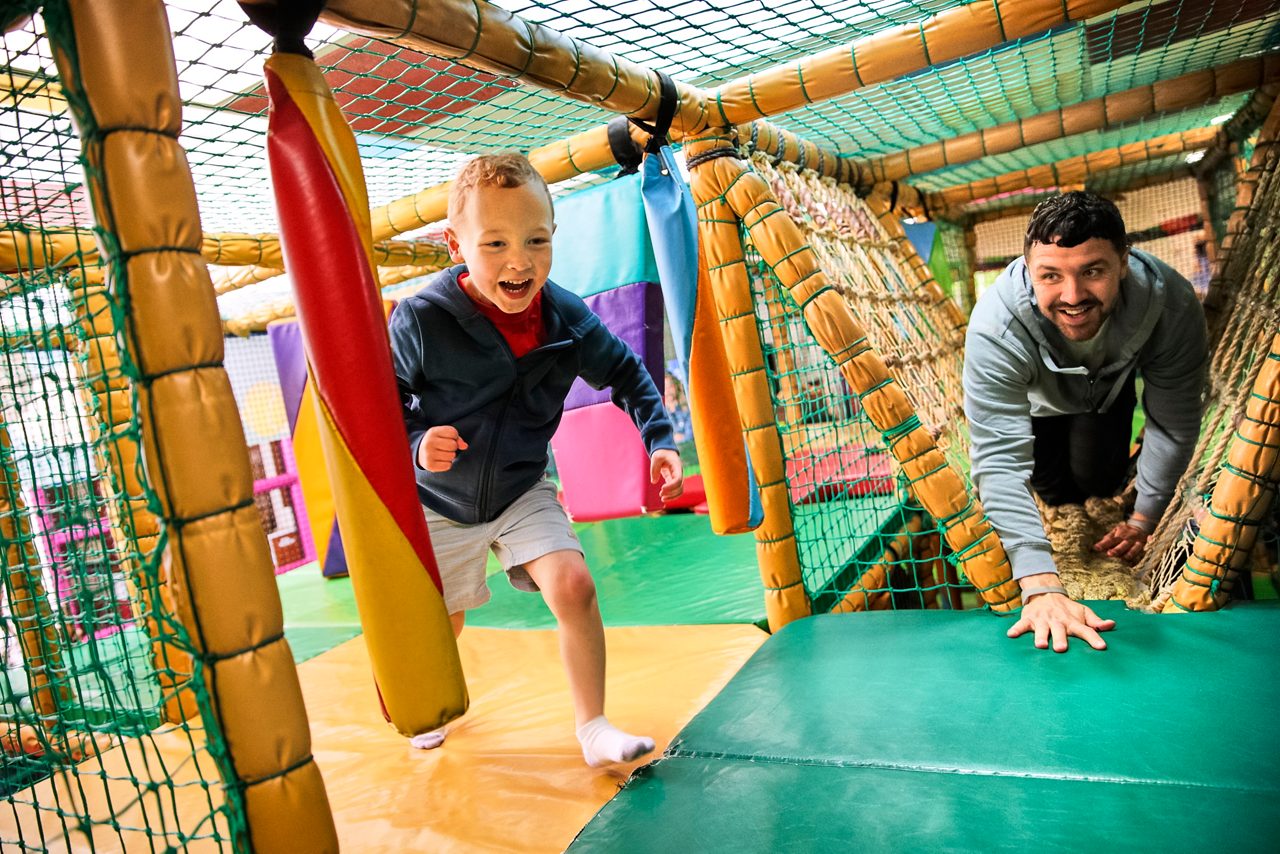A little boy playing in the soft play. 